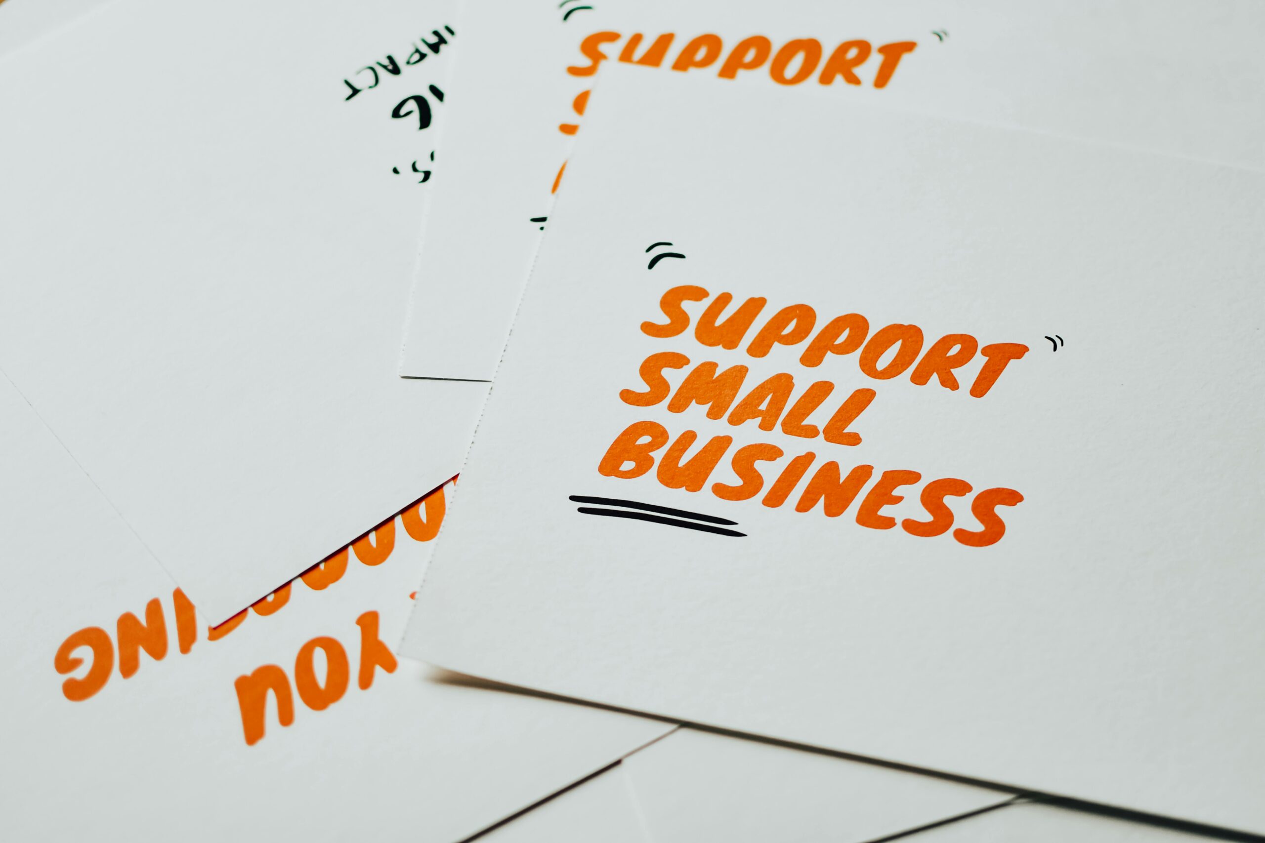 Close-up of motivational cards promoting support for small business on white background.